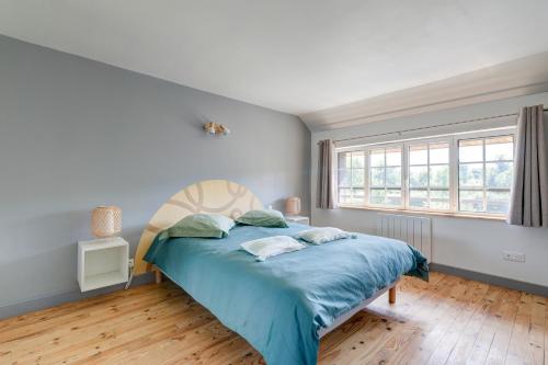 a bedroom with a bed with blue sheets and a window at L'Orée du Bois - Avec Jardin in Rouvroy-sur-Serre