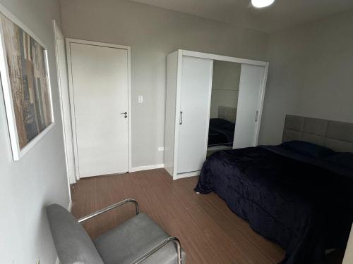 a bedroom with a bed and a chair in it at Frente ao mar, conforto e paz apto 12 in Praia Grande