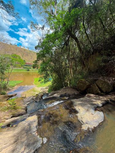 a river with rocks and trees on the side at Pousada Shangri-lá in Cunha