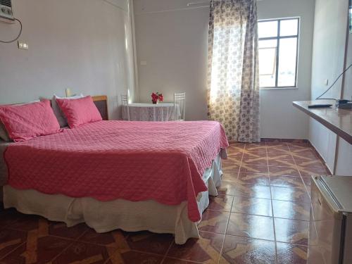 a bedroom with a bed with pink sheets and a window at Gutemberg Palace Hotel in Nova Serrana