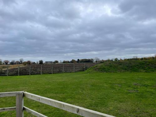 a fence in a field with green grass at Three bedroom cabin with rural views and hot tub in Algarkirk
