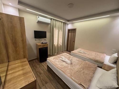 Una habitación de hotel con dos camas y un televisor. en ArQa pyramids Hotel, en El Cairo