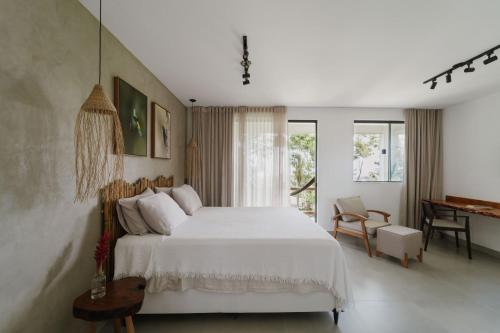 een slaapkamer met een wit bed en een bureau bij Refúgio Wyrá in Itacaré