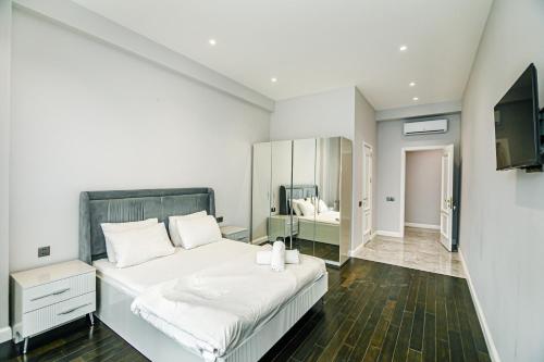 a white bedroom with a large bed and a television at Lux Apartment View Baku Formula 1 Street in Baku