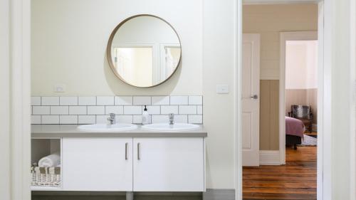 a white bathroom with two sinks and a mirror at Heritage Cottage Daylesford in Daylesford