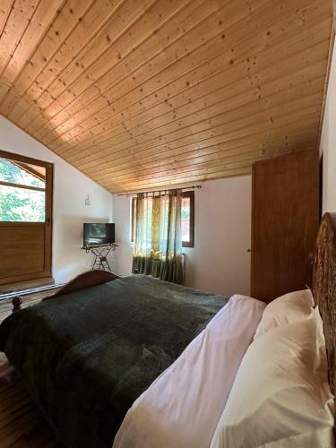 a bedroom with a large bed with a wooden ceiling at Hanul Vanatorului in Gureni