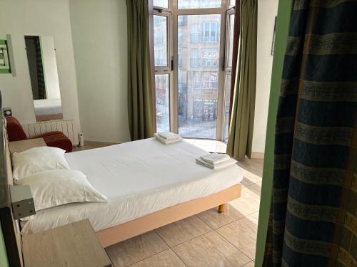 a bed in a room with a large window at Hotel Couleurs Sud Centre-ville Gare Charleville-Mézières in Charleville-Mézières