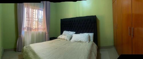 a bedroom with a bed with white sheets and a window at Laala Homes in Kampala