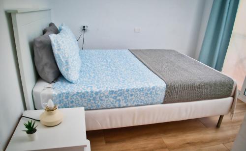 una piccola camera da letto con un letto con un piumone blu di Casa Min26 a Caleta De Fuste