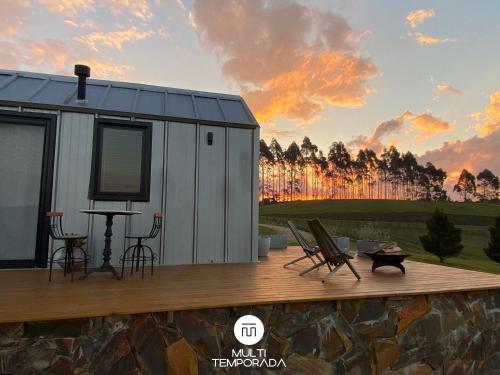 a tiny house with a table and chairs on a deck at Via Kairós - Rancho Queimado - SC in Rancho Queimado