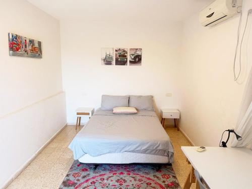 a small bedroom with a bed and a desk at Spacious 3BD Penthouse with Rooftop & Parking in Ra‘ananna