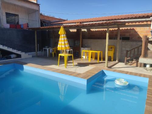 a swimming pool with a table and a yellow umbrella at Casa refúgio in Ibicoara