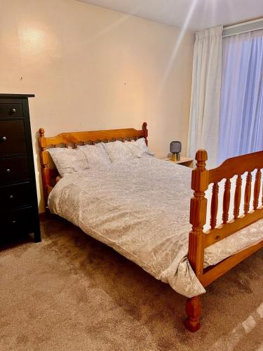 a bedroom with a wooden bed and a window at Dartford Cozy One-Bedroom Flat - Sleeps 2 in Sutton at Hone