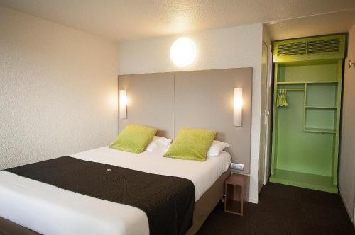 a bedroom with a large bed with two green pillows at Campanile Rouen Sud - Cléon Elbeuf in Cléon