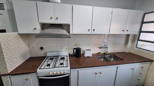 a kitchen with white cabinets and a stove and a sink at Mejor zona de Paraná in Paraná