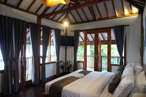 a bedroom with a bed in a room with windows at Tasola Boutique Hotel in Sorongjukung