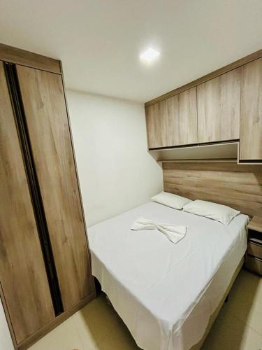 a bedroom with a white bed with wooden cabinets at Flat Monte Castelo Completo em Gravatá Wi-Fi Rápido Ar Estacionamento in Sairé