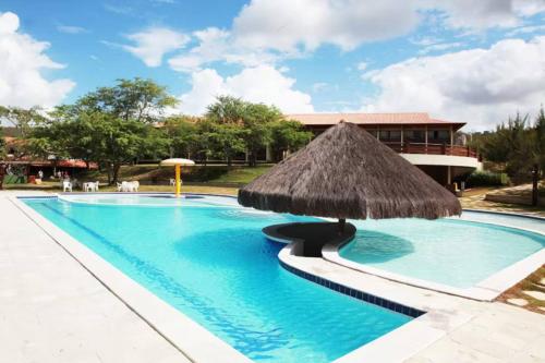 a large swimming pool with a straw umbrella at FLAT NO CONDOMÍNIO MONTE CASTELO MODULO 1 TÉRREO GRAVATÁ - Pe in Sairé