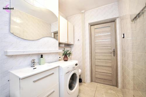 a bathroom with a washing machine and a mirror at MMRent Apartament CityLight in Gdańsk