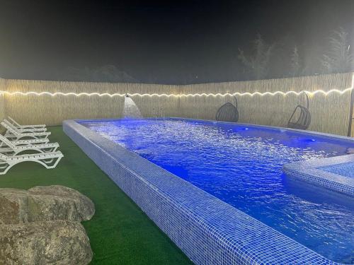 a large swimming pool with a fountain in a yard at Pearl House in Muruntau