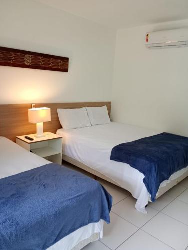 a bedroom with two beds and a lamp on a table at RM Beach Paradise - Barra Iloa Residense in Barra de São Miguel