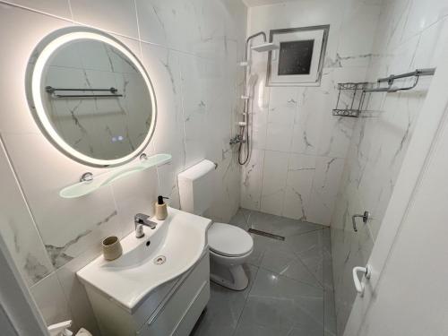 Un baño blanco con lavabo y espejo. en Robinson Ina 2, en Selca kod Bogomolja