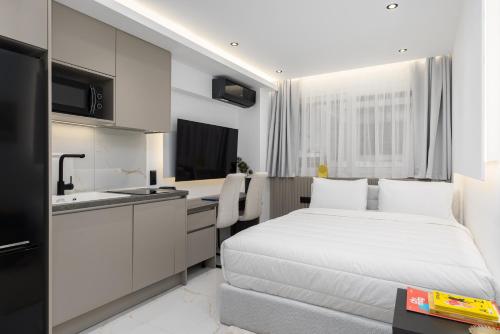 a bedroom with a white bed and a kitchen at Amelie Studios by halu! in Thessaloniki