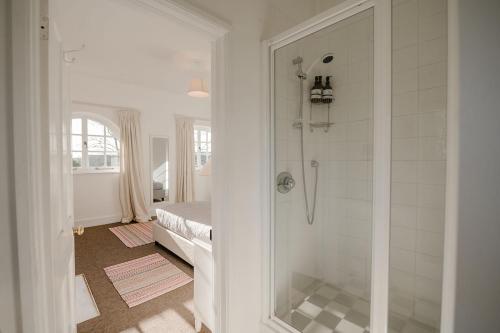a bathroom with a walk in shower next to a bed at Butley Priory Cottage in Woodbridge