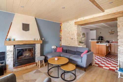 a living room with a couch and a fireplace at Longère de charme avec piscine, proche océan in Lairoux