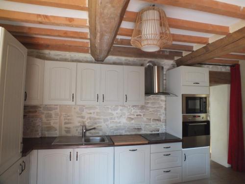 cocina con armarios blancos y pared de piedra en Gîte de charme Floréales Les Myosotis, en Asnelles