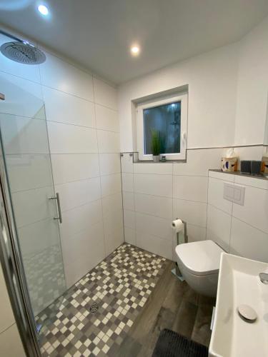 ein Badezimmer mit Dusche, Toilette und Fenster in der Unterkunft Frieslandliebe in Schortens