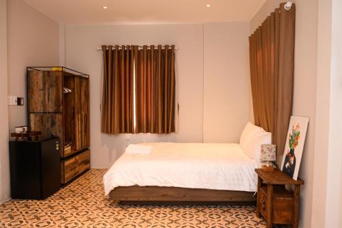 a bedroom with a bed and a dresser and curtains at The Lion Mui Ne in Hòn Lao