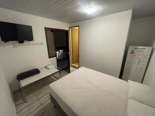 ein kleines Zimmer mit einem Bett und einem Fernseher in der Unterkunft Pousada Dona Maria in Paraty