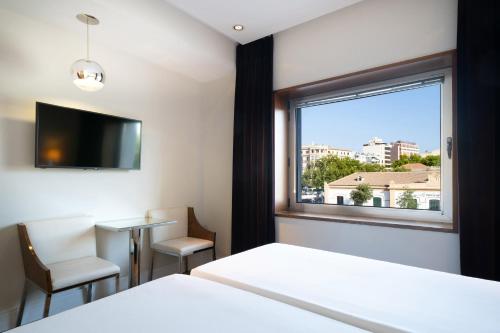 a room with a window and a bed and a tv at Hotel Palma Avenidas in Palma de Mallorca