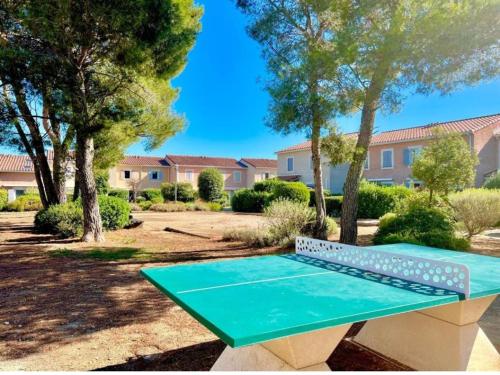 a green bench in a park with trees and buildings at Harmonie in Calvisson