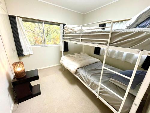 ein Schlafzimmer mit zwei Etagenbetten und einem Fenster in der Unterkunft The Black Wolf in Hakuba