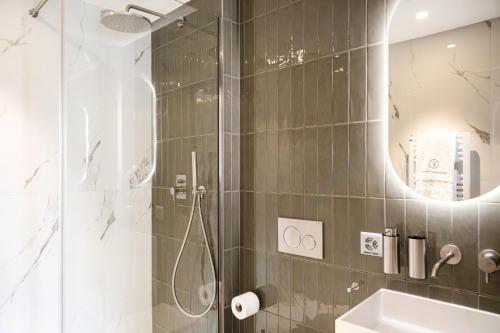 a bathroom with a shower and a sink and a mirror at VISIONAPARTMENTS Lugano - contactless check-in in Lugano