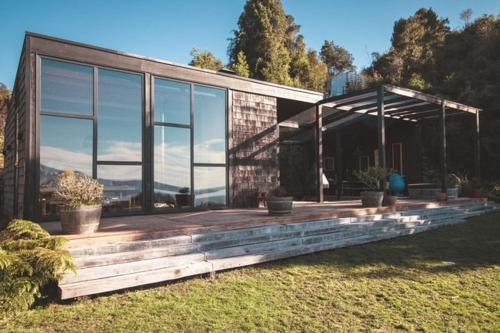 una casa con ventanas de cristal y plantas en macetas en una terraza en Ampe Lodge, en Puerto Varas