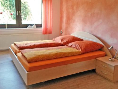 une chambre avec un lit avec un mur orange dans l'établissement Ferienwohnung Familie Balko, à Herdringen
