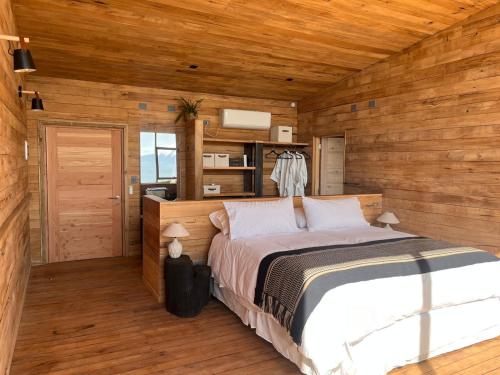 a bedroom with a bed in a wooden cabin at Ampe Lodge in Puerto Varas