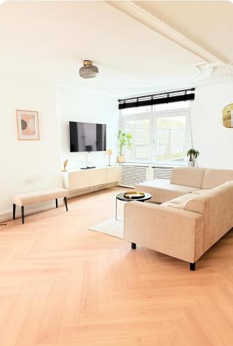 a white living room with a couch and a tv at Canal House The Manor in Amsterdam