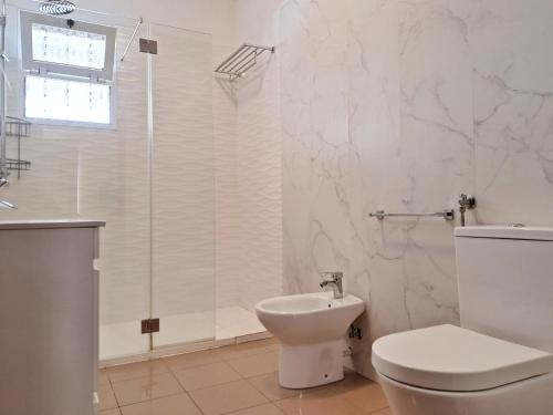 Un baño blanco con inodoro y ducha. en Skyline Home Funchal, en Funchal