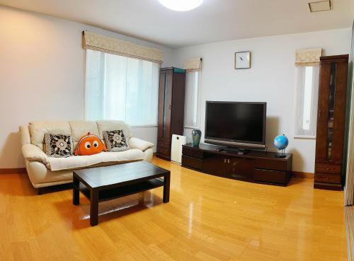 a living room with a couch and a flat screen tv at Aki House居住型民泊小岩駅まで送迎あり in Tokyo