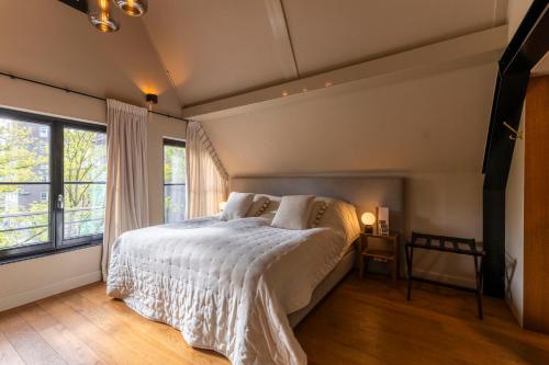 a bedroom with a bed with white sheets and windows at Townhouse 't Raap in Amsterdam