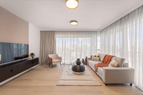Una sala de estar con un sofá y un televisor. en Savyon View 2 Bdr By Isrentals, en El Muṣrāra