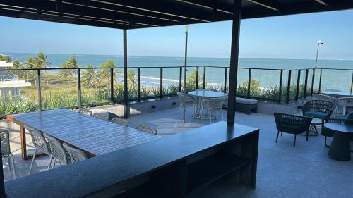 a patio with tables and chairs and a view of the ocean at Flat - Beira-Mar - Piscina - Intermares in Cabedelo