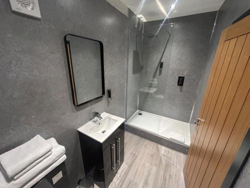 a bathroom with a sink and a shower and a mirror at Dockside Aparthotel, Best Western Signature Collection in Liverpool