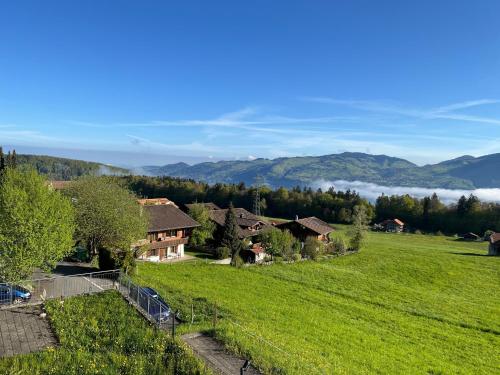 un campo verde con casas y montañas en el fondo en Pfrundmatte 12, en Aeschi bei Spiez