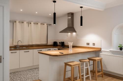 een keuken met witte kasten en een aanrecht met krukken bij St Michaels House in Leeds