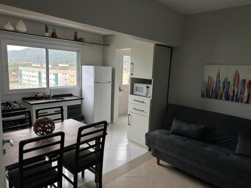 Una cocina y una sala de estar con una mesa y un sofá. en Frente ao Mar - Acorde Com o Barulho das Ondas apto 10, en Praia Grande